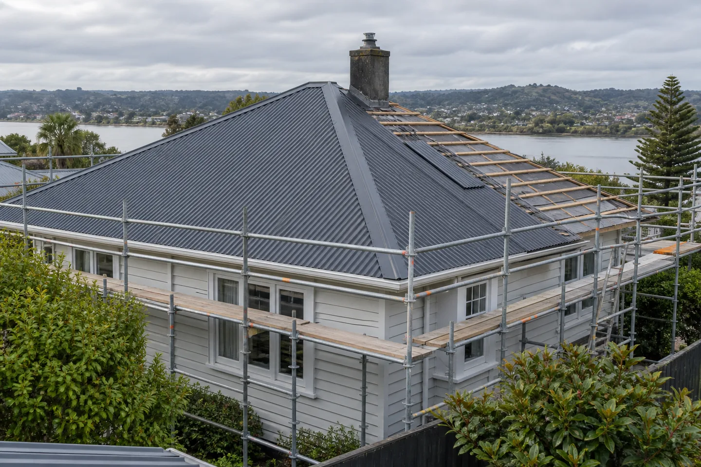 Roofing concept: A weatherboard home with a partly renewed metal roof and perimeter scaffold